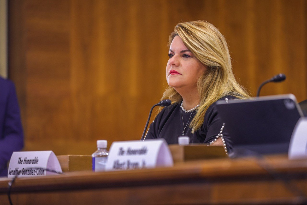 Jenniffer Gonzalez Colon assise à une table du Sénat derrière un chevalet.